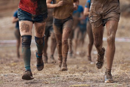 Foto de Grupo de participantes en una carrera de obstáculos. Corren muy fangosos. Concepto de dureza y esfuerzo - Imagen libre de derechos