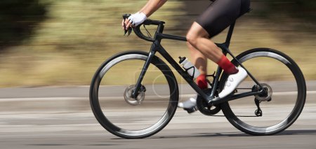 Photo for Motion blur of a bike race with the bicycle and rider at high speed. Professional male cyclist in racing outfit during a ride on bike outdoors. Panning technique used - Royalty Free Image