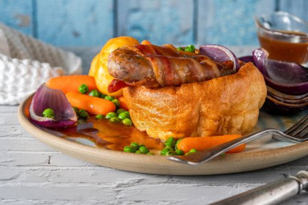 Photo for Toad in the hole with Yorkshire pudding, sausages and vegetables - Royalty Free Image