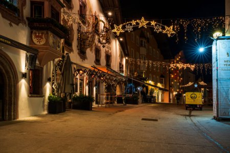Foto de KITZBUHEL, AUSTRIA - JANUARY 07, 2023: Night view of Kitzbuhel, a small Alpine town. Upscale shops and cafes line the streets of its medieval center. - Imagen libre de derechos
