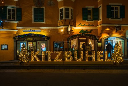 Foto de KITZBUHEL, AUSTRIA - 08 DE ENERO DE 2023: Vista nocturna de la decoración callejera de Navidad en Kitzbuhel, una pequeña ciudad alpina en Austria. Tiendas y cafeterías de lujo bordean las calles de su centro medieval. - Imagen libre de derechos