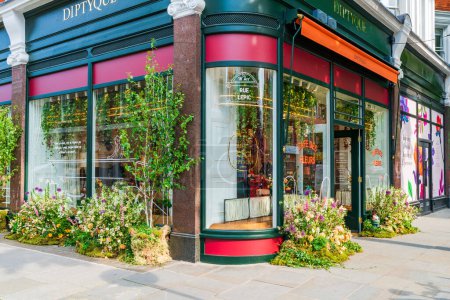 Foto de LONDRES, Reino Unido - 24 de mayo de 2023: Una espectacular exhibición floral decora la ventana de una tienda en Chelsea durante la exposición anual de arte floral Chelsea in Bloom en Londres - Imagen libre de derechos
