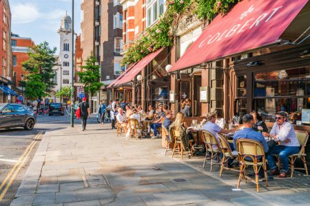 Foto de LONDRES, Reino Unido - 24 de mayo de 2023: La gente disfruta de un soleado día de primavera en Chelsea, una zona afluente conocida por sus elegantes boutiques y restaurantes de alta gama que bordean la concurrida King 's Road - Imagen libre de derechos