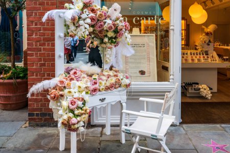 Foto de LONDRES, Reino Unido - 24 de mayo de 2023: Una espectacular exhibición floral decora la ventana de una tienda en Chelsea durante la exposición anual de arte floral Chelsea in Bloom en Londres - Imagen libre de derechos