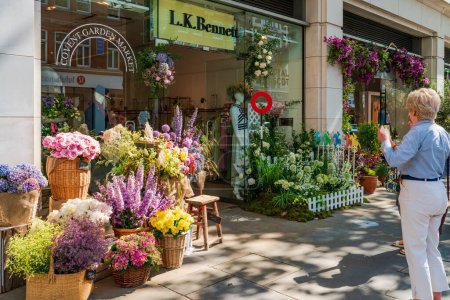 Foto de LONDRES, Reino Unido - 24 de mayo de 2023: Una exhibición floral decora la ventana de una tienda en Chelsea durante la exposición anual de arte floral Chelsea in Bloom en Londres - Imagen libre de derechos