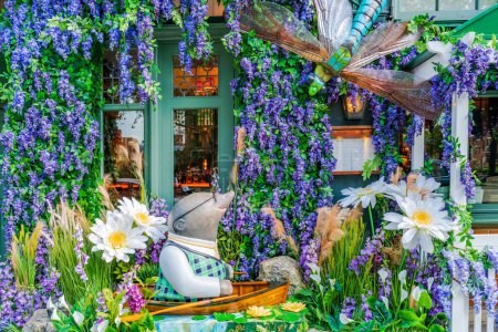 Foto de LONDRES, Reino Unido - 24 de mayo de 2023: Una espectacular exhibición floral decora la ventana del restaurante The Ivy en Chelsea durante la exposición anual de arte floral Chelsea in Bloom en Londres - Imagen libre de derechos