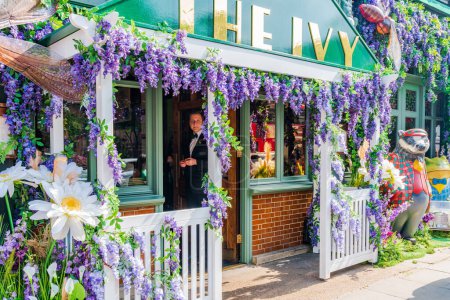 Foto de LONDRES, Reino Unido - 24 de mayo de 2023: Una espectacular exhibición floral decora la ventana del restaurante The Ivy en Chelsea durante la exposición anual de arte floral Chelsea in Bloom en Londres - Imagen libre de derechos