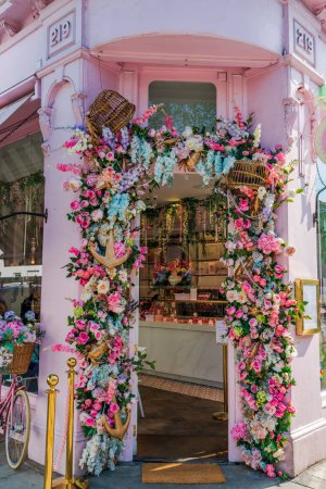Foto de LONDRES, Reino Unido - 24 de mayo de 2023: Una espectacular exhibición floral decora la ventana de la panadería Peggy Porschen en Chelsea durante la exposición anual de arte floral Chelsea in Bloom en Londres - Imagen libre de derechos