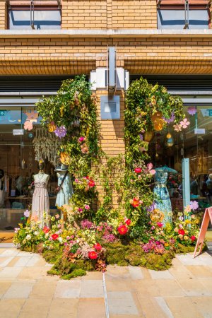 Foto de LONDRES, Reino Unido - 26 de mayo de 2023: Una exhibición floral decora la ventana de una tienda en Chelsea durante la exposición anual de arte floral Chelsea in Bloom en Londres - Imagen libre de derechos