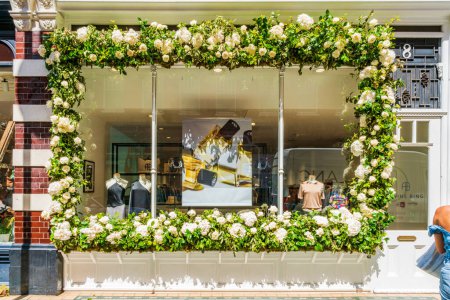 Foto de LONDRES, Reino Unido - 26 de mayo de 2023: Una exhibición floral decora la ventana de una tienda en Chelsea durante la exposición anual de arte floral Chelsea in Bloom en Londres - Imagen libre de derechos