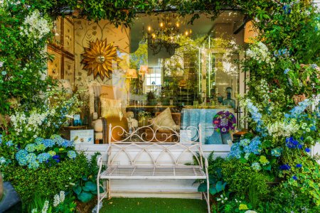 Foto de LONDRES, Reino Unido - 26 de mayo de 2023: Una espectacular exhibición floral decora la ventana de una tienda en Chelsea durante la exposición anual de arte floral Chelsea in Bloom en Londres - Imagen libre de derechos