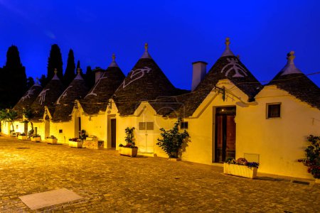 Famous historical old dry stone trulli houses with conical roofs in Alberobello, Italy. Night view
