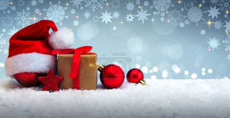 Téléchargez les photos : Chapeau de Père Noël et décoration de Noël rouge isolé sur fond de neige grise
. - en image libre de droit
