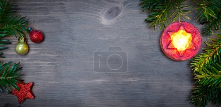 Foto de Rama de abeto con decoraciones navideñas y vela sobre fondo marrón madera vieja con espacio de copia para texto - Imagen libre de derechos