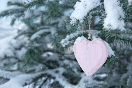 Foto de Pink heart on snow covered pine branch in winter forest. Valentines day background. - Imagen libre de derechos