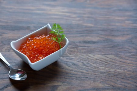 Téléchargez les photos : Red Caviar in bowl over wood background. Close-up salmon caviar - en image libre de droit