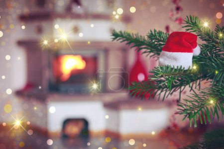 Téléchargez les photos : Branche d'arbre de Noël avec chapeau rouge et fond de cheminée flou. - en image libre de droit