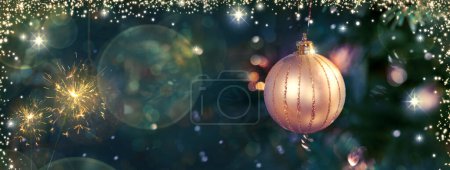 Foto de Rama de árbol de Navidad con bola dorada sobre fondo borroso. - Imagen libre de derechos
