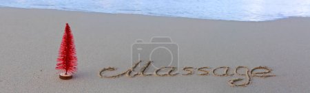 Téléchargez les photos : Mot massage écrit sur le sable de la plage. Plage et arbre de Noël rouge. - en image libre de droit