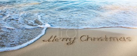 Téléchargez les photos : Joyeux noël écriture dans le sable blanc des Caraïbes . - en image libre de droit