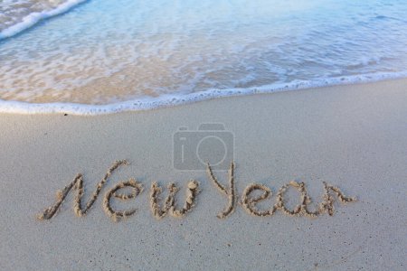 Foto de Palabra de año nuevo escrita en la arena de la playa. Fondo de playa y olas. - Imagen libre de derechos