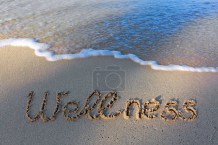 Foto de Palabra de bienestar escrita en la arena de la playa. Fondo de playa y olas. - Imagen libre de derechos