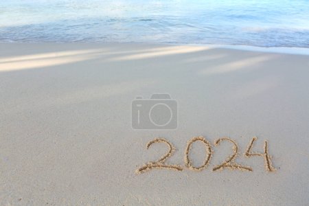 Foto de Feliz Año Nuevo 2024 texto en la playa del mar. Inscripción manuscrita 2024 en la hermosa playa de arena blanca - Imagen libre de derechos