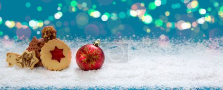 Foto de Fondo de Navidad con bola roja y galletas sobre nieve blanca. - Imagen libre de derechos
