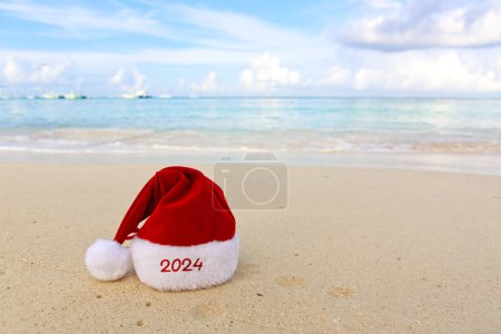 Foto de Feliz sombrero de Navidad en la arena blanca del Caribe. Año Nuevo 2024 fondo - Imagen libre de derechos