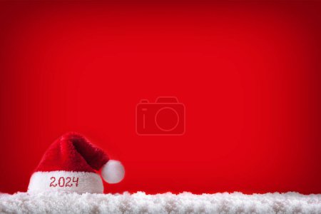Photo for Santa hat on white snow isolated on red background. Happy new Year 2024 . - Royalty Free Image