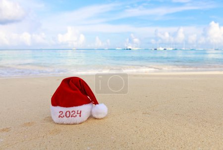 Foto de Feliz sombrero de Navidad en la arena blanca del Caribe. Año Nuevo 2024 fondo - Imagen libre de derechos