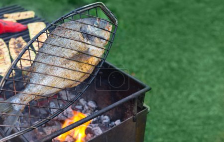 Photo for Dorado fish is grilled on charcoal grill on a sunny summer day. - Royalty Free Image