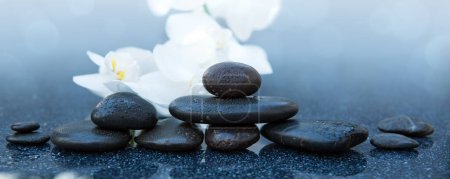 Foto de Flores de orquídea blanca y piedras de spa sobre un fondo gris, espacio para un texto. - Imagen libre de derechos