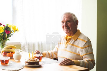 Seniorin feiert Geburtstag und sitzt lächelnd und glücklich am Tisch.