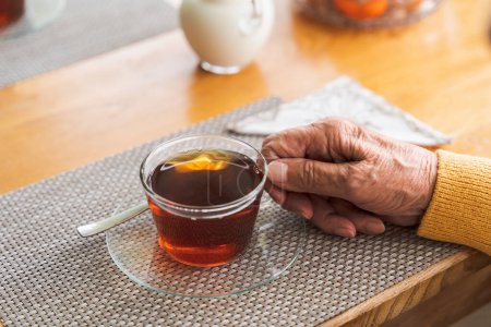 Téléchargez les photos : Gros plan de la main d'un grand-père âgé tenant une tasse de thé. - en image libre de droit