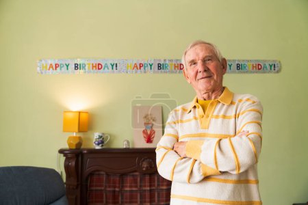 Photo for Celebrating Grandfathers jubilee in a cozy home interior. Senior citizen, smiling happily, looks at the camera. - Royalty Free Image