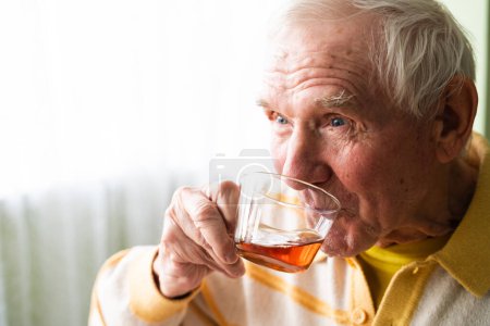 Photo for Portrait of happy an elderly man, sits at the table and drinking a tea. Morning routine. - Royalty Free Image