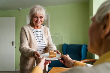 Foto de Feliz cumpleaños de la tercera edad, la esposa trató a su marido anciano a un pastel festivo. - Imagen libre de derechos