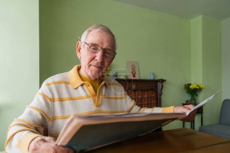 Foto de Un pensionista leyendo prensa fresca en casa, rutina doméstica. Concepto de centenarios. - Imagen libre de derechos