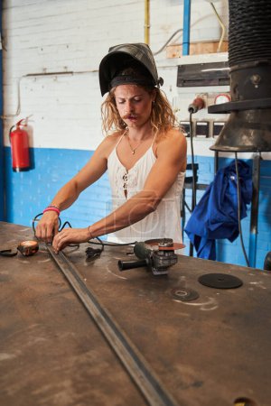 Photo for Professional feminine carpenter is enjoying his job. Longhaired man with moustaches posing at his workplace. Stock photo - Royalty Free Image