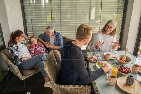 Photo for Cheerful senior woman in eyeglasses looking at her son and talking with wide smile. People relationships concept - Royalty Free Image