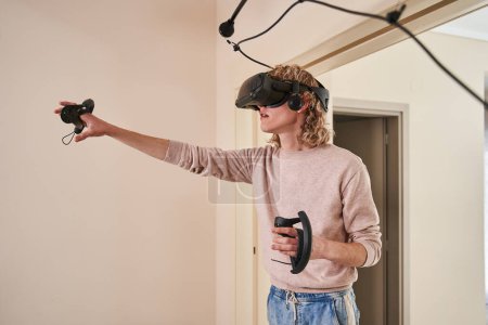 Photo for Young boy using a virtual reality headset play games in Metaverse at home, future digital technology background - Royalty Free Image