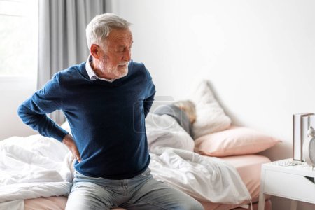 Foto de Sick unhappy senior adult elderly man touching her muscle injury Lower back suffering from muscles back pain at home.physical injury and healthcare problem - Imagen libre de derechos