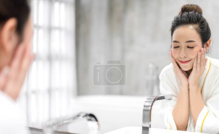 Téléchargez les photos : Portrait de sourire de beauté heureuse jolie femme asiatique propre fraîche et saine soin de la peau blanche spa lavage visage propre avec de l'eau et devant le miroir dans la salle de bain.beauté et spa.perfect peau fraîche - en image libre de droit
