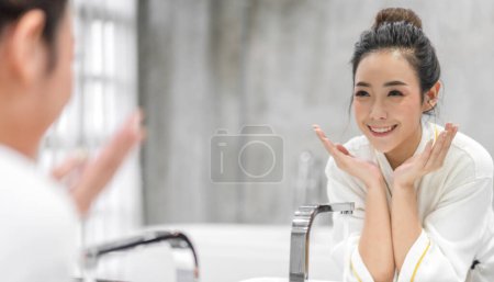 Téléchargez les photos : Portrait de sourire de beauté heureuse jolie femme asiatique propre fraîche et saine soin de la peau blanche spa lavage visage propre avec de l'eau et devant le miroir dans la salle de bain.beauté et spa.perfect peau fraîche - en image libre de droit