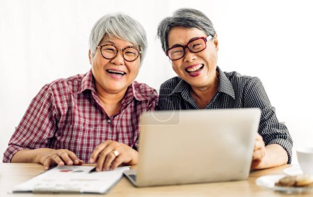 Téléchargez les photos : Portrait de deux amis heureux personnes âgées âgées asiatiques femmes souriantes et travaillant avec ordinateur portable à la maison.Concept de retraite - en image libre de droit