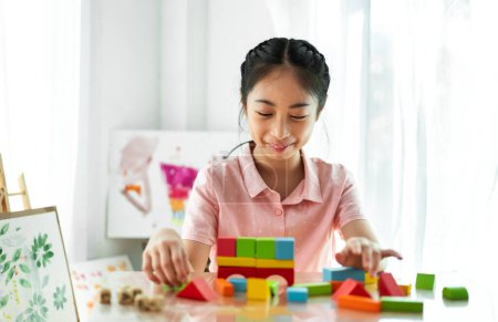 Téléchargez les photos : Portrait de profiter heureux asiatique petite fille asiatique souriant jouer avec jouet construire en bois bloc jeu de société à la maison - en image libre de droit