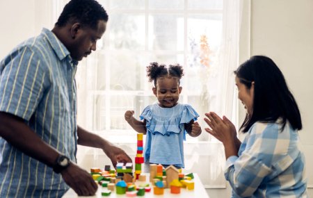 Téléchargez les photos : Portrait d'amour heureux famille noire afro-américaine père et mère avec petite fille souriante activité apprendre et compétences cerveau entraînement jouer avec jouet construire des blocs en bois jeu d'éducation à la maison - en image libre de droit