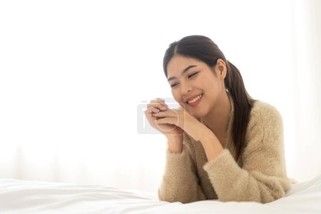 Téléchargez les photos : Portrait de sourire gai belle belle femme asiatique propre peau blanche fraîche et saine posant sourire en pyjama clothes.Girl abattage se détendre et profiter du temps sur le lit à la beauté home.asia - en image libre de droit