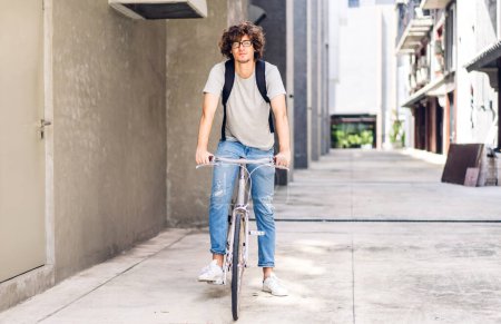 Téléchargez les photos : Portrait de décontracté hipster bel homme d'affaires avec sac à dos impatient tout en faisant la navette à vélo sur la route de la ville de la rue aller au travail.concept de vélo de transport de voyage d'affaires - en image libre de droit